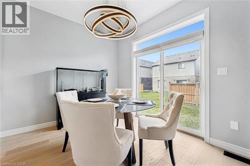 Dining area featuring light wood-finish flooring, a contemporary chandelier, a sliding glass door, and backyard access - 628 Florencedale Crescent, Kitchener, ON 