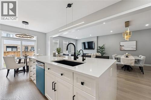 Kitchen island featuring a black sink and faucet, white cabinetry with black hardware, and light-colored countertops - 628 Florencedale Crescent, Kitchener, ON 