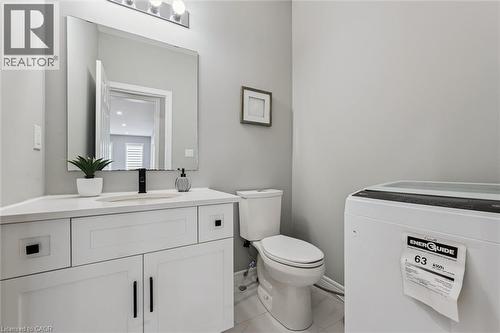 Bathroom featuring a white vanity with a light-toned countertop, a rectangular mirror, a chrome light fixture with three bulbs, a single-handle matte black faucet, and light gray wall paint - 628 Florencedale Crescent, Kitchener, ON 