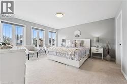 Light-filled room featuring three large windows with roller shades, neutral carpeting, and light gray wall paint - 