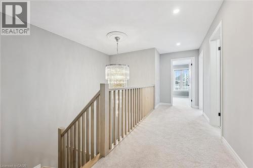 Upper-level hallway featuring a contemporary chandelier with ceiling medallion, light-toned wood banister, neutral carpeting, and recessed lighting - 628 Florencedale Crescent, Kitchener, ON 