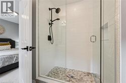 Glass-enclosed shower with a matte black shower system, textured white subway tile, a recessed shower niche, and hexagonal floor tiling - 