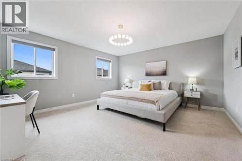 Spacious room featuring light gray walls, plush carpet flooring, two windows with blinds, a modern ceiling light fixture, and white baseboards - 628 Florencedale Crescent, Kitchener, ON 