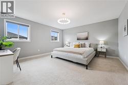 Spacious room featuring light gray walls, plush carpet flooring, two windows with blinds, a modern ceiling light fixture, and white baseboards - 