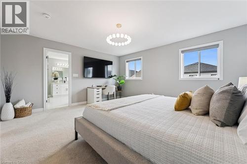 Spacious bedroom featuring light gray walls, plush carpeting, a modern ceiling light fixture, and two windows - 628 Florencedale Crescent, Kitchener, ON 
