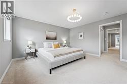 Bedroom featuring light gray walls, plush carpet flooring, and a modern circular ceiling light fixture - 