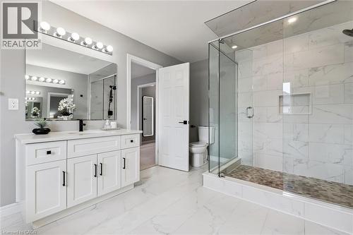 Spacious bathroom featuring a frameless glass shower enclosure with white marble-look tile, a built-in shower niche, and a stone mosaic shower floor - 628 Florencedale Crescent, Kitchener, ON 