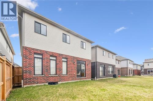 Red brick and light-colored siding exterior, featuring multiple windows with dark frames, a ground-level sliding glass door, and a wooden fence bordering the property - 628 Florencedale Crescent, Kitchener, ON 