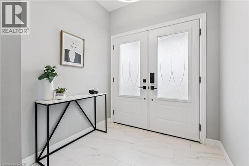 Bright entryway featuring double doors with decorative glass inserts, matte black hardware, white baseboards, and white tile flooring - 628 Florencedale Crescent, Kitchener, ON 