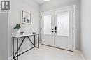 Bright entryway featuring double doors with decorative glass inserts, matte black hardware, white baseboards, and white tile flooring - 628 Florencedale Crescent, Kitchener, ON 