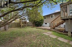 Spacious backyard featuring a wood privacy fence, mature trees, and a multi-level wooden play structure - 