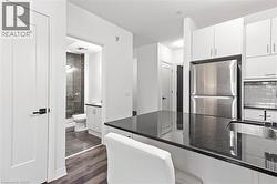 Kitchen featuring freestanding refrigerator, white cabinetry, dark wood finished floors, dark stone countertops, and decorative backsplash - 