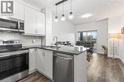 Kitchen featuring stainless steel appliances, a peninsula, dark countertops, and decorative backsplash - 