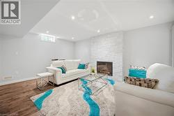 Spacious room featuring a stone-clad fireplace, wood-finish flooring, recessed lighting, and a window - 