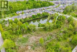Aerial perspective showcasing a residential area with a prominent natural pond surrounded by lush green foliage - 
