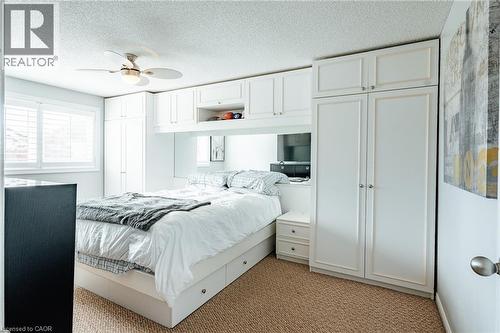 Integrated white cabinetry surrounding the bed frame, featuring multiple storage options - 560 Penny Lane, Waterloo, ON 