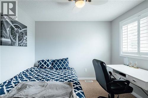 Light-filled room featuring a built-in window with white plantation shutters, a ceiling fan with integrated lighting, and carpet flooring - 560 Penny Lane, Waterloo, ON 
