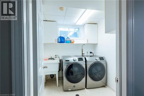 Dedicated laundry room featuring a utility sink, upper cabinetry, and a window - 560 Penny Lane, Waterloo, ON 