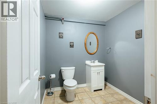Bathroom featuring a white vanity with integrated sink, an oval framed mirror, and light-toned tile flooring - 560 Penny Lane, Waterloo, ON 