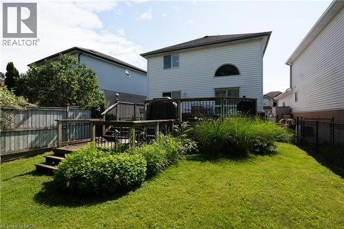 Rear exterior featuring a multi-level wood deck, a landscaped garden, and a lawn area - 560 Penny Lane, Waterloo, ON 