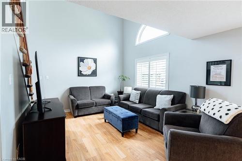 Vaulted ceiling living area featuring wood-finish flooring, plantation shutters, and a high arched transom window - 560 Penny Lane, Waterloo, ON 