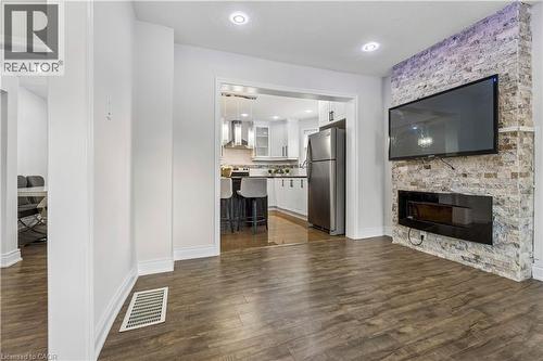 Spacious living area featuring wood-finish flooring, recessed lighting, and a modern fireplace with a stone-accented wall - 180 Campbell Avenue, Hamilton, ON - Indoor Photo Showing Living Room With Fireplace