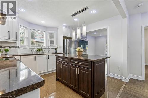 Kitchen featuring an island with a dark wood-finish cabinet base and stone-finish countertop - 180 Campbell Avenue, Hamilton, ON - Indoor Photo Showing Kitchen With Upgraded Kitchen