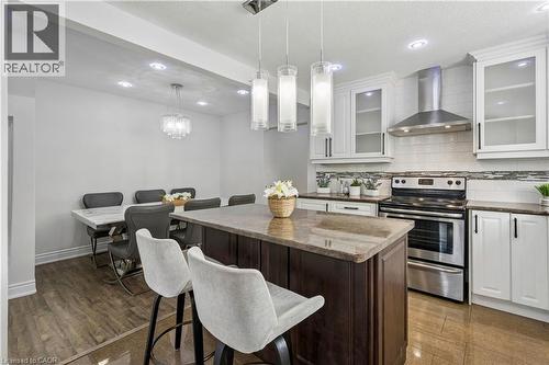 Kitchen featuring a center island with a stone countertop, white cabinetry with glass inserts, stainless steel appliances, and tile flooring - 180 Campbell Avenue, Hamilton, ON - Indoor Photo Showing Kitchen With Upgraded Kitchen