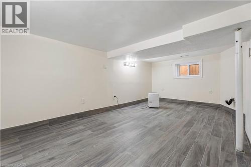 Spacious room featuring gray wood-finish tile flooring and a matching tile baseboard - 180 Campbell Avenue, Hamilton, ON - Indoor