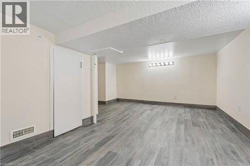 Spacious interior room featuring wood-finish tile flooring and light-toned walls - 180 Campbell Avenue, Hamilton, ON - Indoor