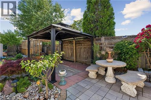 Outdoor gazebo structure with a dark metal frame and solid roof, situated on a red paver patio - 180 Campbell Avenue, Hamilton, ON - Outdoor With Deck Patio Veranda