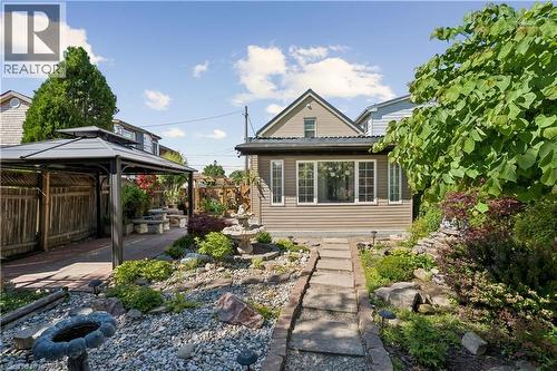 Inviting backyard featuring extensive landscaping, a stone pathway, and a central water feature - 180 Campbell Avenue, Hamilton, ON - Outdoor