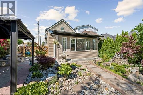 Expansive backyard featuring a stone pathway, diverse plantings, a multi-tiered fountain, and a gazebo with brick paver flooring - 180 Campbell Avenue, Hamilton, ON - Outdoor