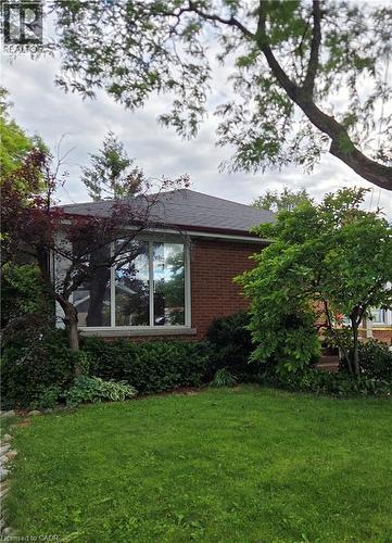 Brick exterior featuring a bay window, dark shingle roof, and established landscaping - 56 Everton Place, Hamilton, ON 