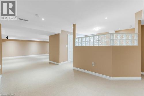Expansive carpeted area featuring a glass block partition, recessed lighting, white baseboards, and a white interior door - 227 Chestnut Hill Crescent, Kitchener, ON - Indoor