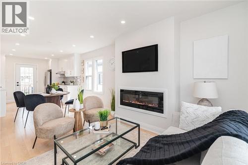 Open-concept living area featuring a built-in linear electric fireplace, recessed lighting, and wood-finish flooring - 297 Britannia Avenue, Hamilton, ON 