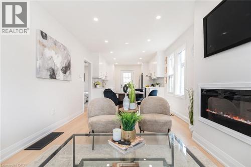 Living area featuring recessed lighting, light wood-finish flooring, and a contemporary fireplace - 297 Britannia Avenue, Hamilton, ON 