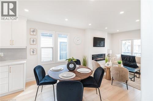 Open concept living space featuring light wood-finish flooring, recessed lighting, a built-in fireplace, and white cabinetry with gold-tone hardware - 297 Britannia Avenue, Hamilton, ON 