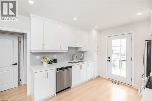 Kitchen featuring white cabinetry, light wood-finish flooring, recessed lighting, and a glass-paned exterior door - 297 Britannia Avenue, Hamilton, ON 