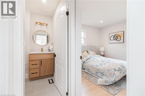 Modern vanity featuring a wood-finish cabinet, white countertop, and gold-finish faucet - 297 Britannia Avenue, Hamilton, ON 