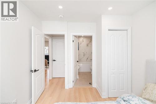 Interior passageway featuring light wood-finish flooring, recessed lighting, and white paneled doors with matte black hardware - 297 Britannia Avenue, Hamilton, ON 