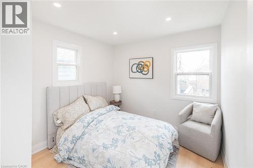 Bright room featuring two windows with white trim, wood-finish flooring, and recessed ceiling lighting - 297 Britannia Avenue, Hamilton, ON 