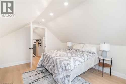 Sloped ceilings with recessed lighting define this room, featuring light wood-finish flooring - 297 Britannia Avenue, Hamilton, ON 