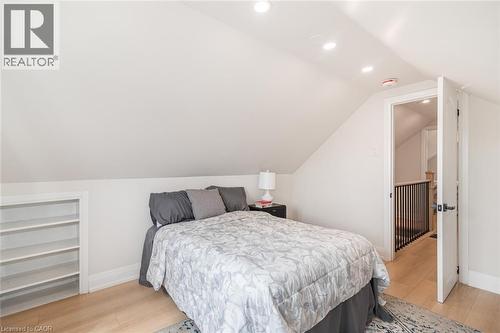 Sloped ceiling room featuring recessed lighting, a built-in shelving unit, and wood-finish flooring - 297 Britannia Avenue, Hamilton, ON 