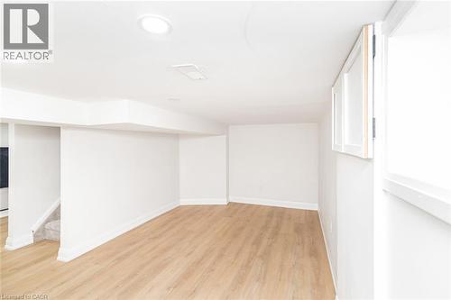 Spacious lower-level area featuring recessed lighting, light wood-finish flooring, white walls, and a window with white trim - 297 Britannia Avenue, Hamilton, ON 