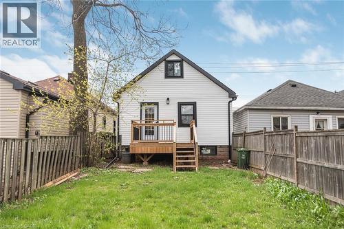 Rear exterior featuring white horizontal siding, a gabled roof with dark shingles, and black trim windows - 297 Britannia Avenue, Hamilton, ON 