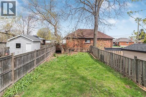 Expansive backyard featuring a green lawn, wood fencing, and mature trees - 297 Britannia Avenue, Hamilton, ON 