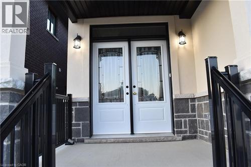 Double entry doors with decorative glass panels, flanked by two outdoor wall lanterns - 8 Dunlop Road, Hamilton, ON - Outdoor With Exterior