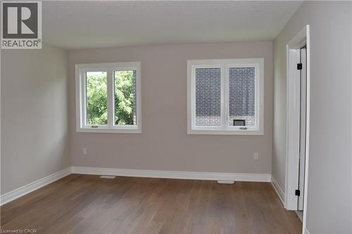 Bright and spacious room featuring hardwood flooring, fresh neutral walls, and abundant natural light from dual windows - 8 Dunlop Road, Hamilton, ON - Indoor Photo Showing Other Room