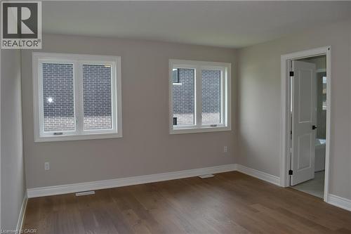 Room featuring wood-finish flooring, two windows with white trim, light gray painted walls, and white baseboards - 8 Dunlop Road, Hamilton, ON - Indoor Photo Showing Other Room